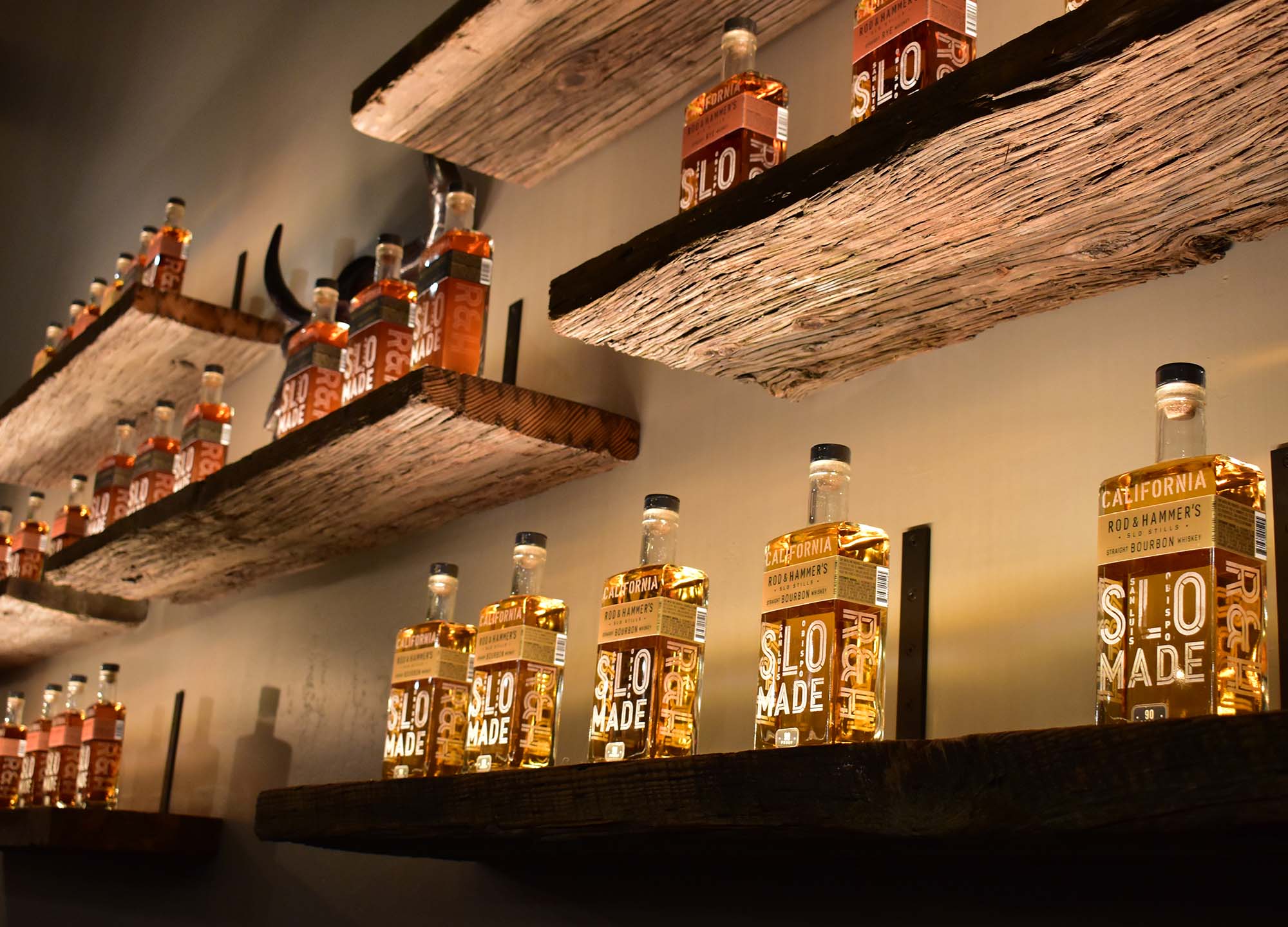 Rod & Hammer’s SLO Stills bourbon bottles on reclaimed wood shelving